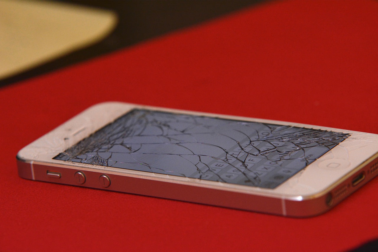 iPhone with a cracked screen displayed on a repair table, indicating professional screen replacement service at Imfixed