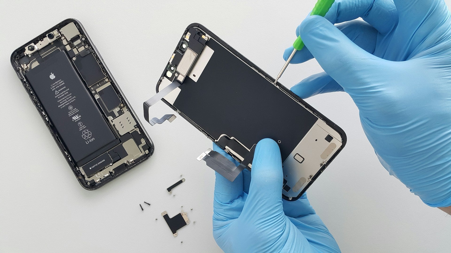 An expert technician carefully removing an iPhone screen using precision tools during a phone repair process at Imfixed.