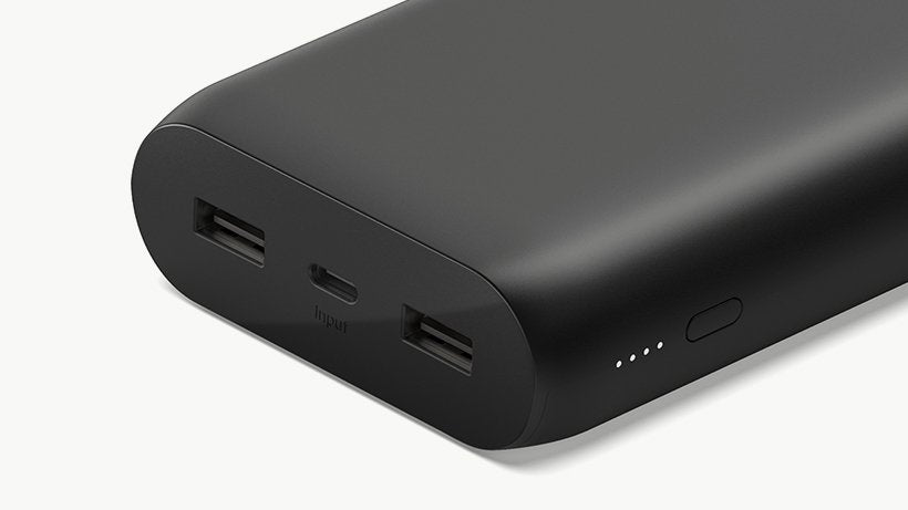 A black portable 20000 mAh power bank with two output ports and a power button on the front.