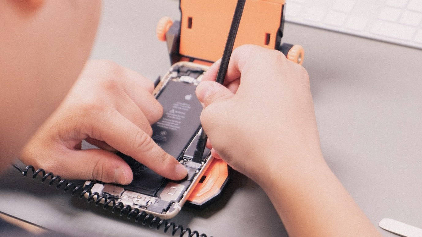 Expert technician repairing an iPhone on a work table at Imfixed repair shop.
