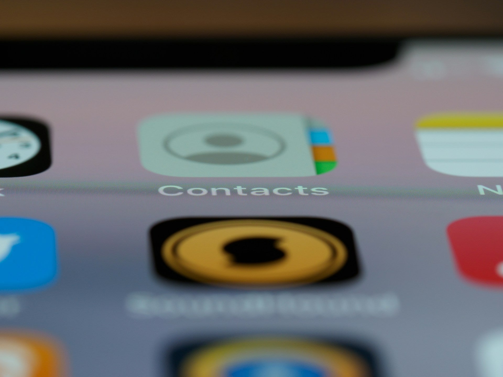 iPhone home screen displaying the Contacts app icon alongside other apps.