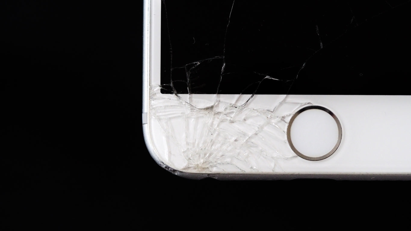 iPhone with a visibly cracked screen lying on a surface, raising concerns about its waterproof capability