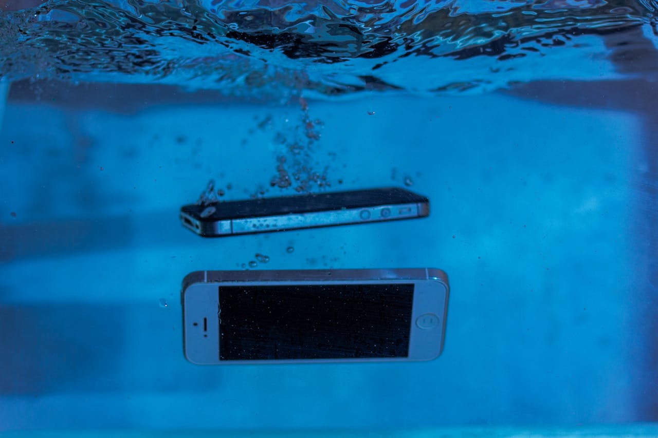 iPhone submerged in water representing water damage and the need for professional repair service