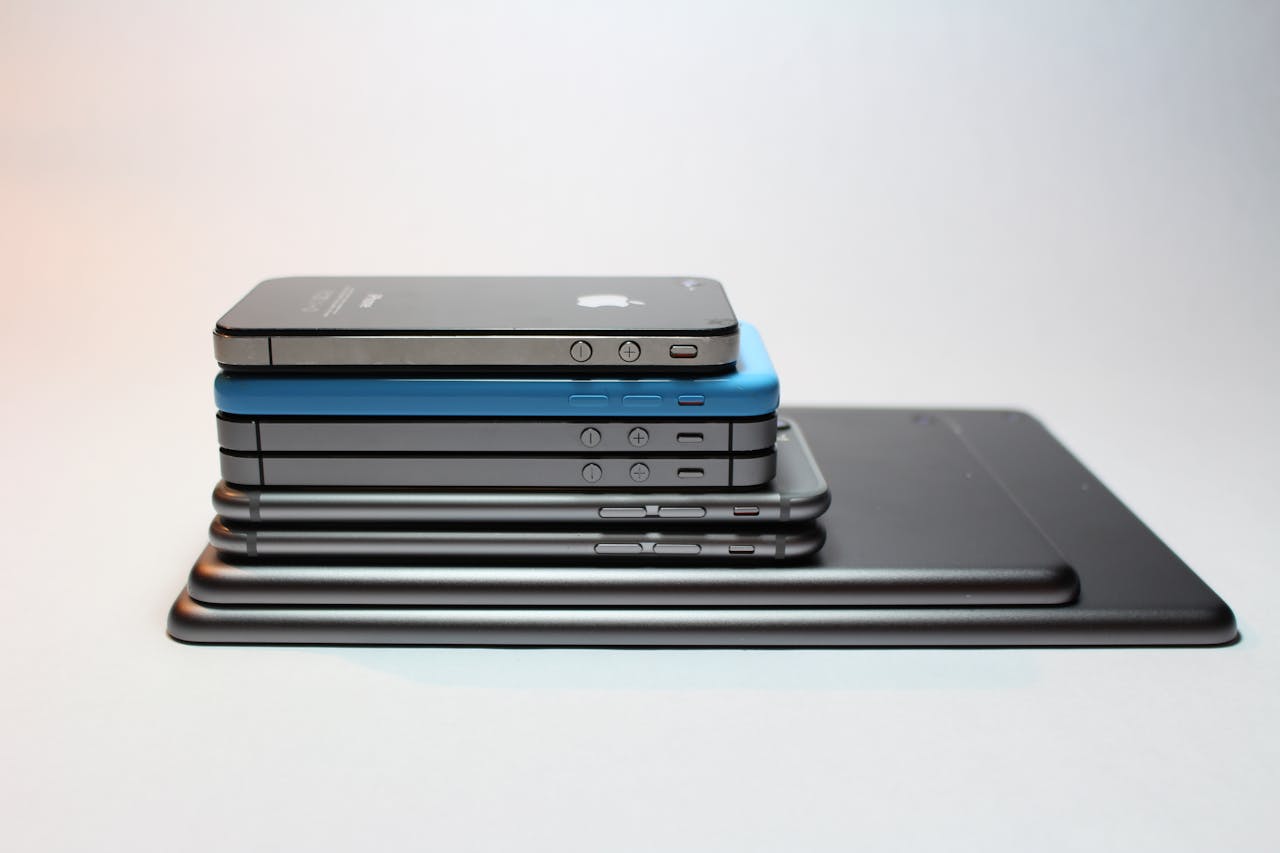 Multiple phones and tablets stacked on a surface, representing device repair options in Manchester