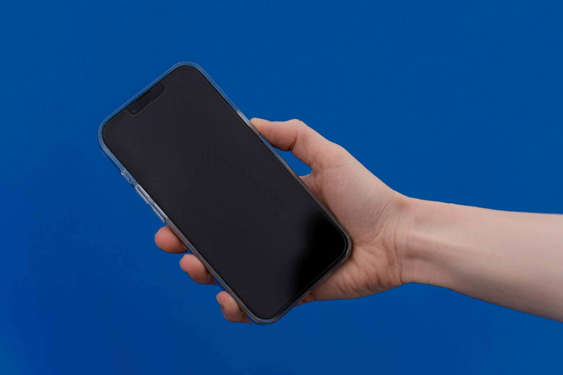 A person holding an iPhone with a completely black and unresponsive screen, illustrating the Black Screen of Death issue.